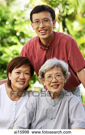 Senior adult with two adult offspring, smiling at camera View Large Photo Image Stock Photo - Senior adult with two adult offspring, smiling at camera. Fotosearch