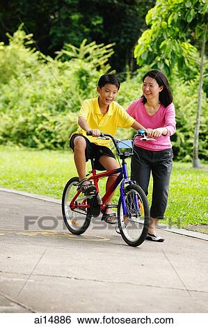 Son on bicycle, mother next to him View Large Photo Image Stock Photograph - Son on bicycle, mother next to him. Fotosearch