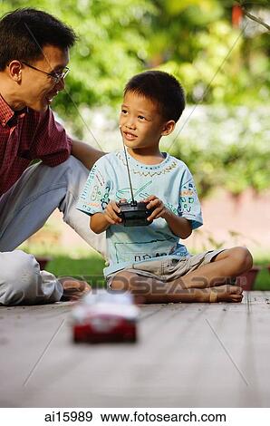 Son playing with remote control toy car, father next to him View Large Photo Image Stock Photo - Son playing with remote control toy car, father next to him. Fotosearch