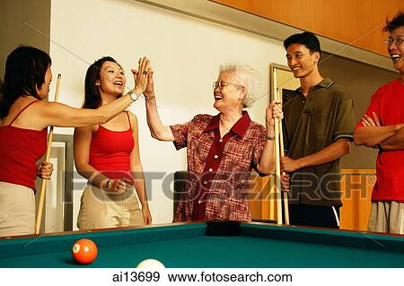Stock Photo - Three generation family around pool table. Fotosearch