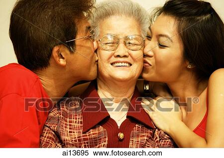 Stock Photography - Three generation family, son and granddaughter kissing grandmother. Fotosearch