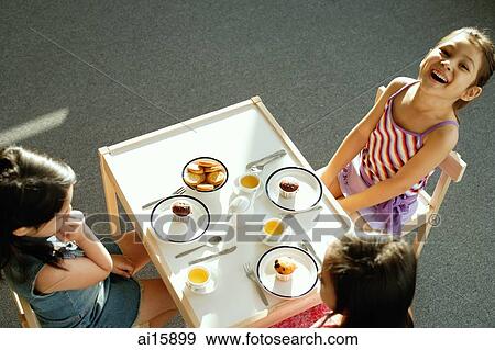 Three girls at tea party, one girl smiling at camera View Large Photo Image Stock Photo - Three girls at tea party, one girl smiling at camera. Fotosearch