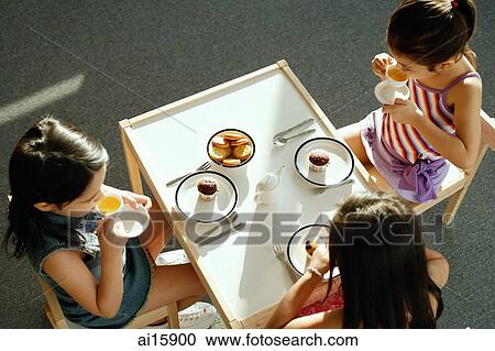 Stock Image - Three girls having a tea party. Fotosearch