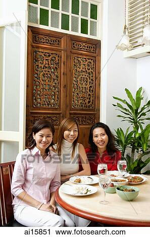Three women at a restaurant sitting, looking at camera View Large Photo Image Stock Image - Three women at a restaurant sitting, looking at camera. Fotosearch