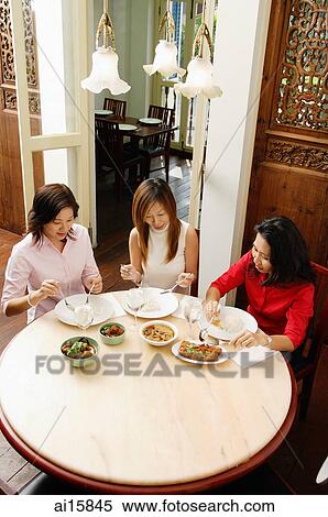 Stock Photography - Three women having a meal at restaurant. Fotosearch