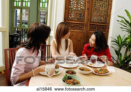 Stock Photograph - Three women having a meal at restaurant, talking. Fotosearch