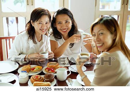 Stock Photography - Three women having tea at cafe, smiling at camera. Fotosearch