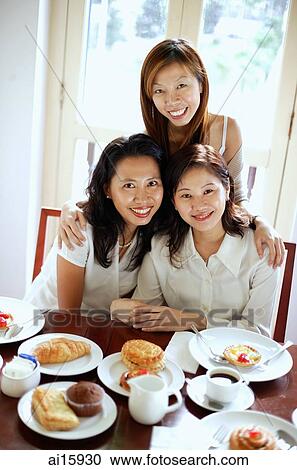 Stock Image - Three women in cafe, smiling at camera, portrait. Fotosearch
