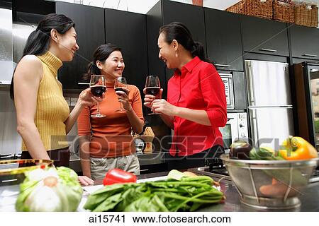 Three women in kitchen, holding wine glasses, talking View Large Photo Image Stock Image - Three women in kitchen, holding wine glasses, talking. Fotosearch