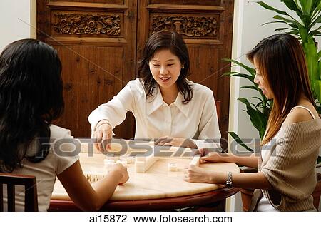 Stock Image - Three women playing mahjong together. Fotosearch