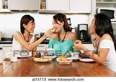 Three women sitting around kitchen table, eating View Large Photo Image Stock Image - Three women sitting around kitchen table, eating. Fotosearch