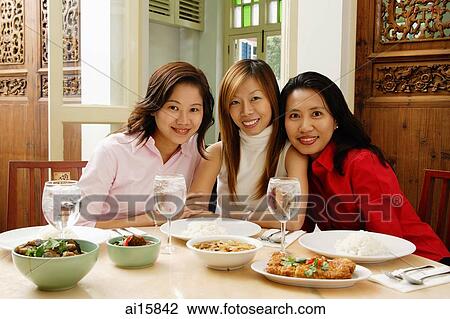 Three women sitting at restaurant table, smiling at camera View Large Photo Image Stock Image - Three women sitting at restaurant table, smiling at camera. Fotosearch