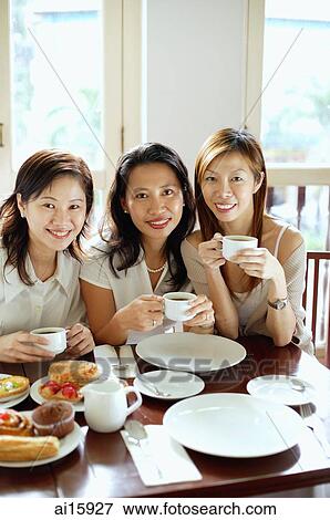 Three women smiling at camera, holding cups, portrait View Large Photo Image Stock Photo - Three women smiling at camera, holding cups, portrait. Fotosearch