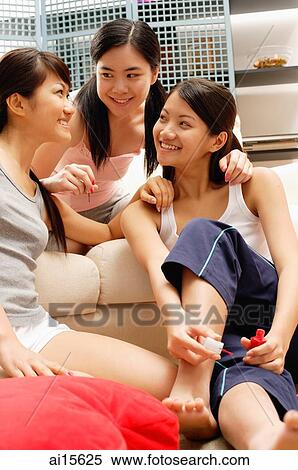 Three young women in living room, one holding nail polish bottle View Large Photo Image Stock Photography - Three young women in living room, one holding nail polish bottle. Fotosearch
