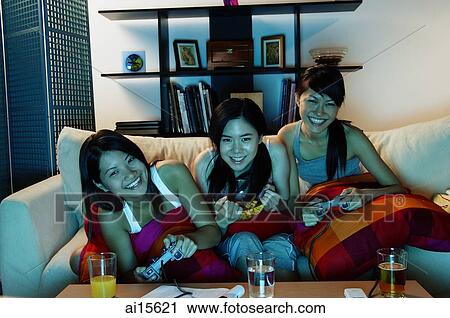 Three young women in living room, playing video games View Large Photo Image Stock Image - Three young women in living room, playing video games. Fotosearch