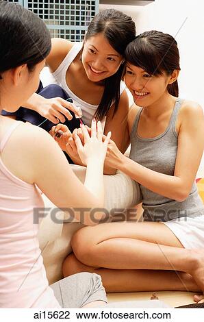Three young women in living room, applying nail polish View Large Photo Image Stock Image - Three young women in living room, applying nail polish. Fotosearch
