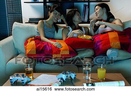 Three young women in living room, sitting on sofa View Large Photo Image Stock Photograph - Three young women in living room, sitting on sofa. Fotosearch