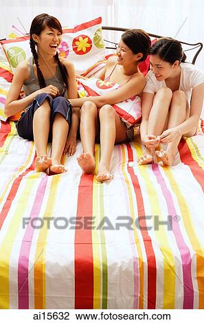 Three young women sitting on bed View Large Photo Image Stock Image - Three young women sitting on bed. Fotosearch