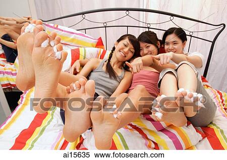 Three young women sitting on bed, showing their feet View Large Photo Image Stock Photography - Three young women sitting on bed, showing their feet. Fotosearch
