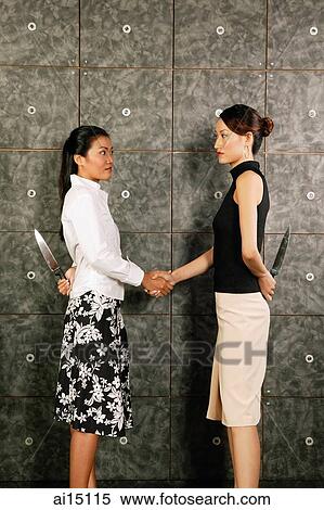 Two female executives shaking hands, holding knives behind their backs View Large Photo Image Stock Photography - Two female executives shaking hands, holding knives behind their backs. Fotosearch
