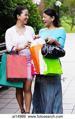 Two friends holding shopping bags, walking side by side View Large Photo Image Stock Photo - Two friends holding shopping bags, walking side by side. Fotosearch