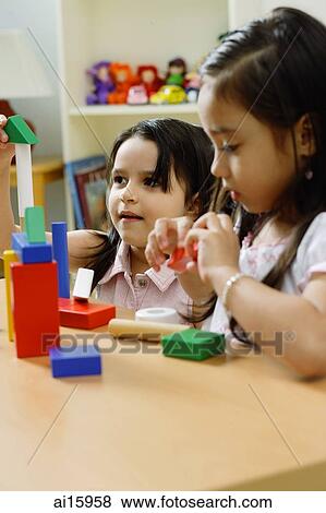 Stock Photo - Two girls side by side, playing with building blocks. Fotosearch