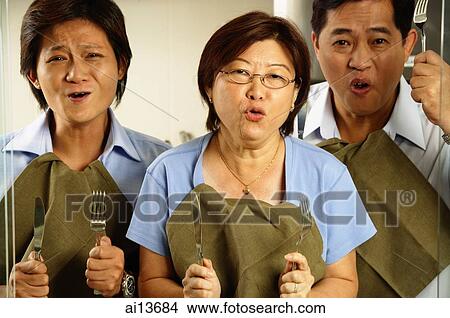 Two men and woman, holding cutlery, making a face View Large Photo Image Picture - Two men and woman, holding cutlery, making a face. Fotosearch