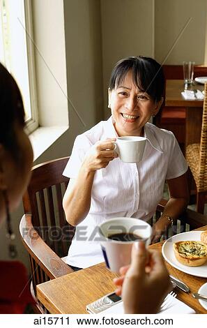 Two women at cafe, drinking coffee View Large Photo Image Stock Image - Two women at cafe, drinking coffee. Fotosearch