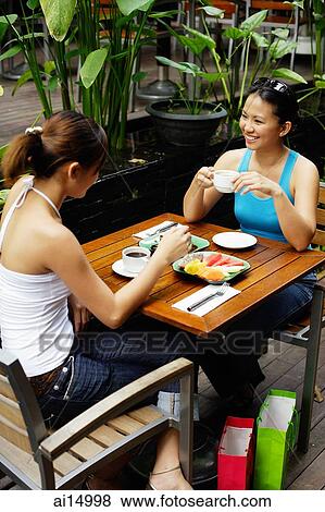 Two women at cafe, having coffee and food View Large Photo Image Stock Photo - Two women at cafe, having coffee and food. Fotosearch