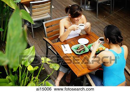Two women at cafe, having coffee and food, high angle view View Large Photo Image Stock Photograph - Two women at cafe, having coffee and food, high angle view. Fotosearch