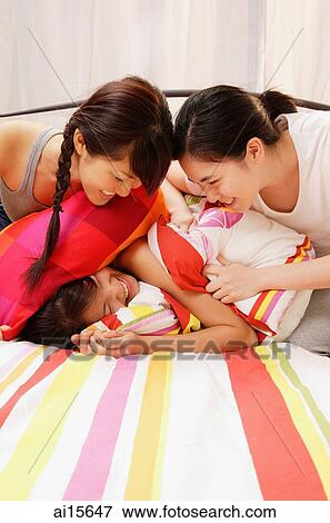 Two women covering another woman with pillows View Large Photo Image Stock Photo - Two women covering another woman with pillows. Fotosearch
