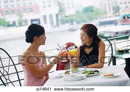 Two women having lunch, toasting with drinks View Large Photo Image Stock Image - Two women having lunch, toasting with drinks. Fotosearch