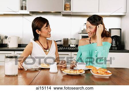 Two women sitting at kitchen table, side by side View Large Photo Image Picture - Two women sitting at kitchen table, side by side. Fotosearch