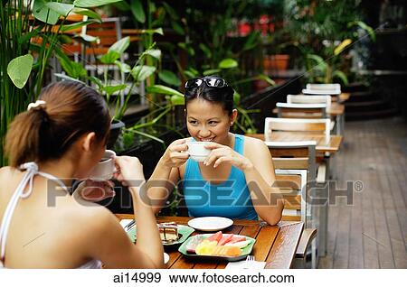 Two women sitting at table, having coffee and fruits View Large Photo Image Stock Photo - Two women sitting at table, having coffee and fruits. Fotosearch