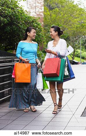 Two women with shopping bags, walking and talking View Large Photo Image Stock Photo - Two women with shopping bags, walking and talking. Fotosearch