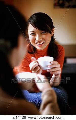 Two young women drinking from cups, face to face, over the shoulder view View Large Photo Image Stock Photograph - Two young women drinking from cups, face to face, over the shoulder view. Fotosearch