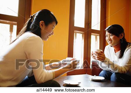 Two young women, holding cups of coffee, talking View Large Photo Image Stock Photo - Two young women, holding cups of coffee, talking. Fotosearch