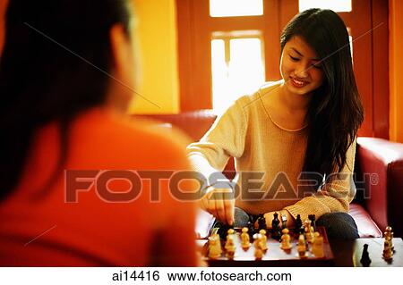 Two young women sitting, playing chess, over the shoulder view View Large Photo Image Stock Photograph - Two young women sitting, playing chess, over the shoulder view. Fotosearch