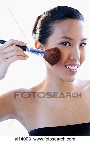 Stock Image - Woman applying make-up with brush. Fotosearch