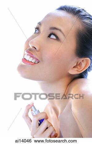 Woman applying perfume, looking up, smiling View Large Photo Image Stock Photograph - Woman applying perfume, looking up, smiling. Fotosearch