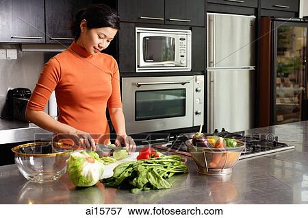 Woman cutting vegetables in kitchen, portrait View Large Photo Image Stock Photo - Woman cutting vegetables in kitchen, portrait. Fotosearch