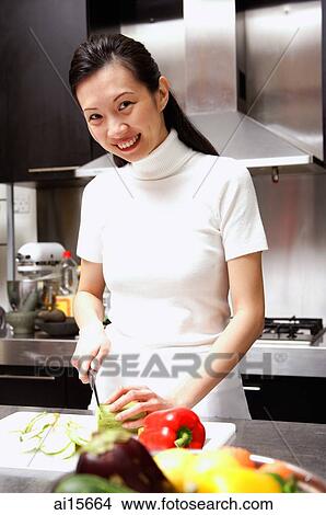 Picture - Woman cutting vegetables looking at camera, smiling. Fotosearch