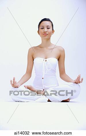 Stock Image - Woman dressed in white, eyes shut and legs crossed. Fotosearch