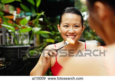 Stock Photo - Woman eating, facing another person. Fotosearch