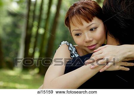 Stock Photo - Woman embracing man, over the shoulder view. Fotosearch