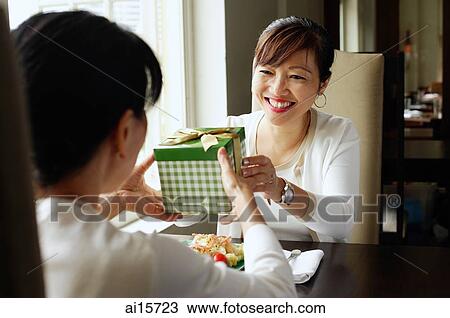 Woman giving gift to person sitting opposite her View Large Photo Image Stock Image - Woman giving gift to person sitting opposite her. Fotosearch