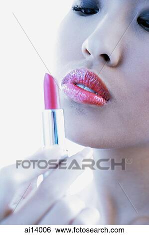Woman holding and looking at lipstick View Large Photo Image Stock Photograph - Woman holding and looking at lipstick. Fotosearch