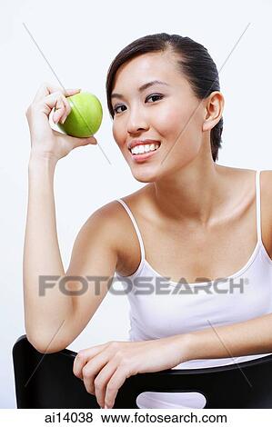 Stock Photo - Woman holding apple, looking at camera. Fotosearch