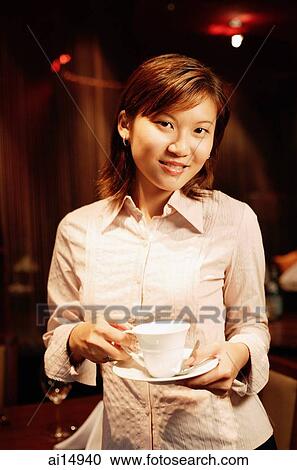 Woman holding cup and saucer, looking at camera View Large Photo Image Stock Image - Woman holding cup and saucer, looking at camera. Fotosearch