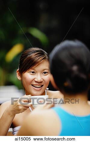 Woman holding cup, sitting across another woman View Large Photo Image Stock Photography - Woman holding cup, sitting across another woman. Fotosearch